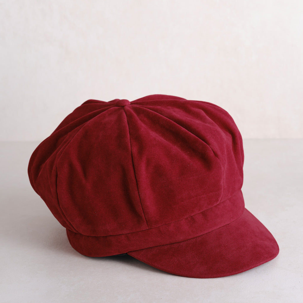 a deep burgundy velvet newsboy cap with grey back ground.