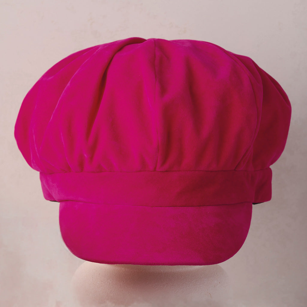 A bright magenta pink pleated chef's hat displayed against a light beige background.
