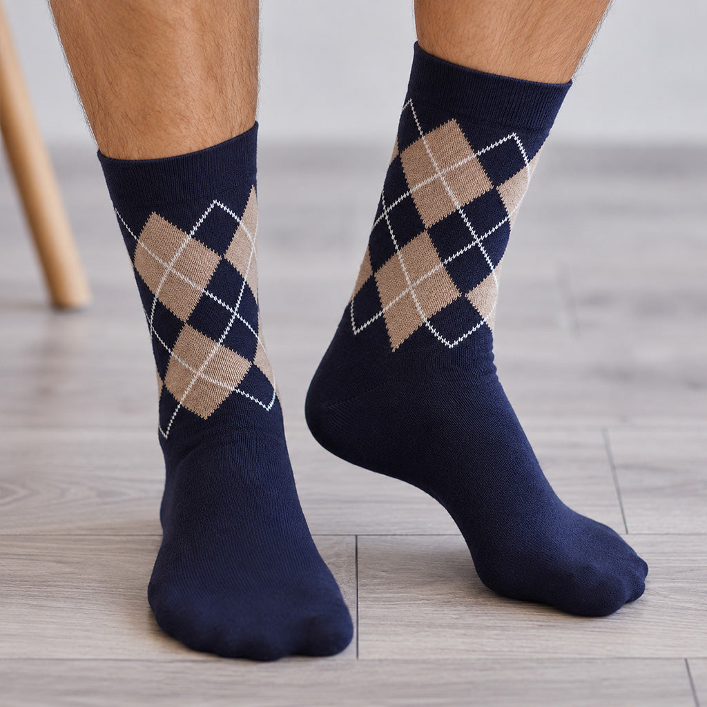 A pair of navy blue crew socks with a beige and white argyle pattern on the upper leg, worn on feet standing on a light wood floor.