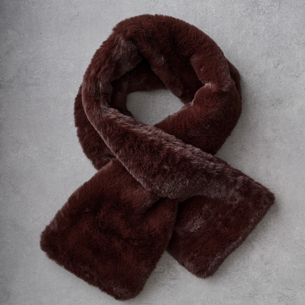 A dark brown faux fur scarf arranged in a loop on a textured gray background.