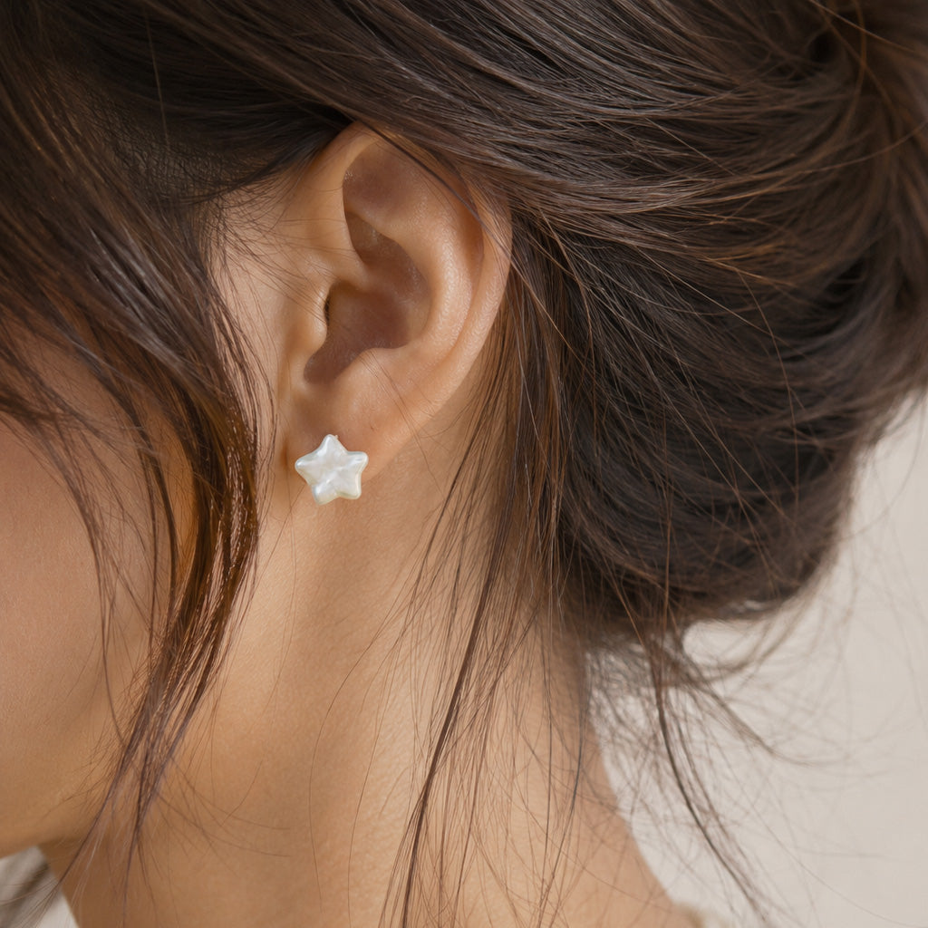 A close-up of a person's ear wearing a small white star-shaped stud earring.