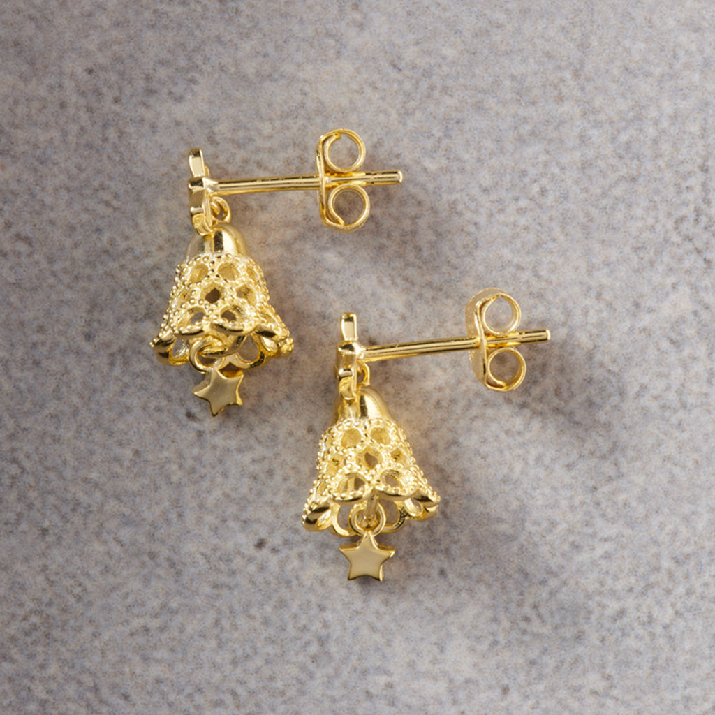 A pair of gold dangle earrings featuring an intricate openwork tree design with a small star charm at the bottom, displayed on a textured gray surface.