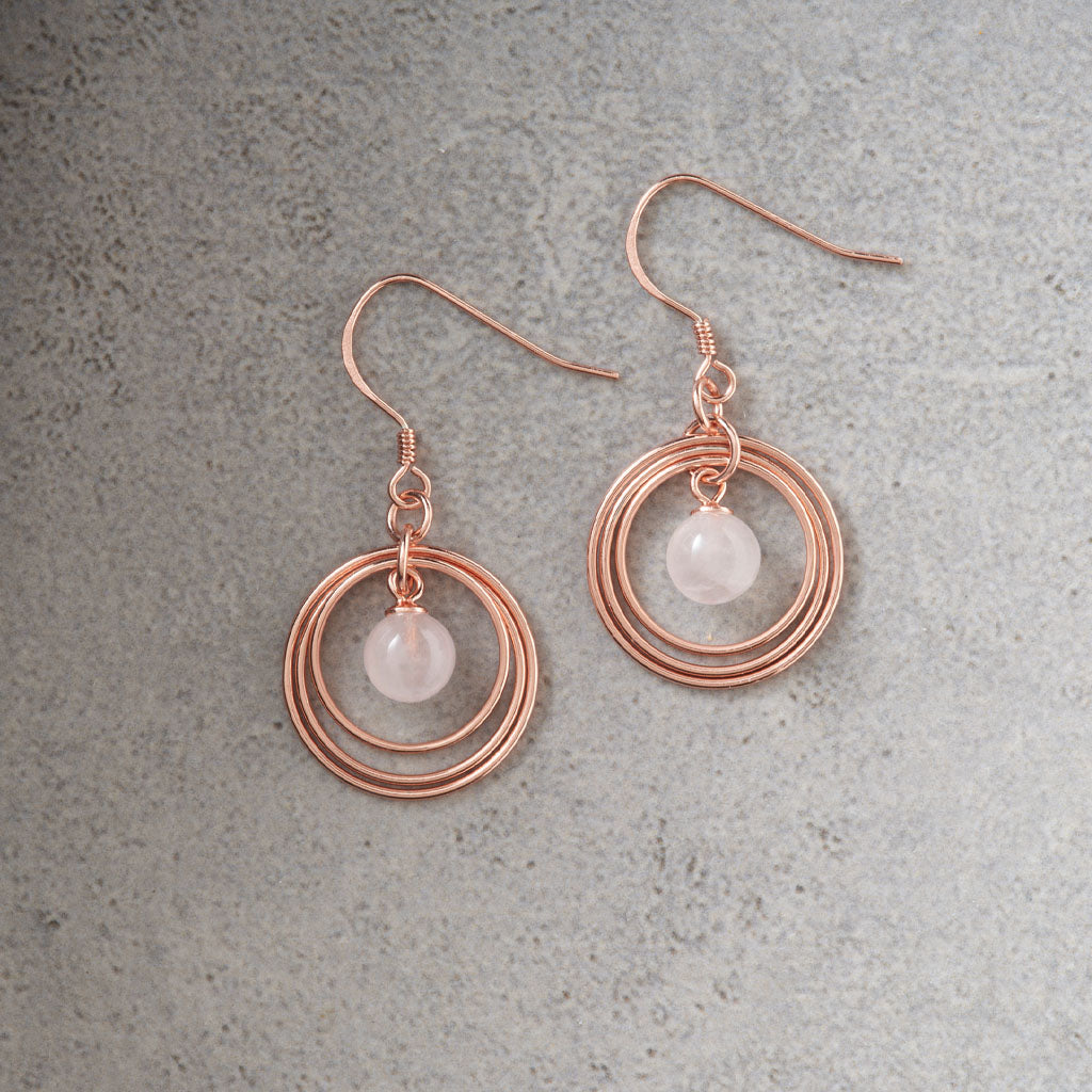 Rose Gold Plated & Rose Quartz Triple Disc Earrings on grey background.