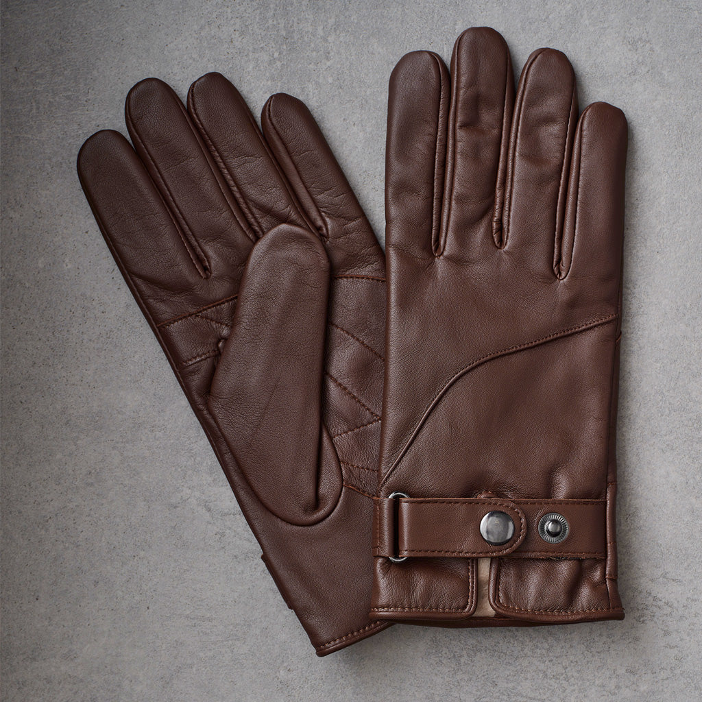A pair of dark brown leather gloves laid flat on a textured gray background, showing the back of one glove and the palm side of the other.