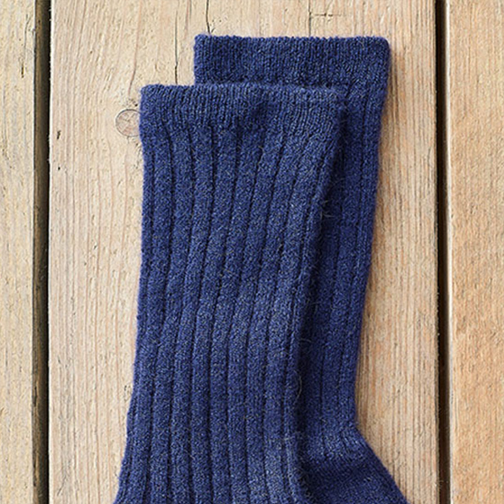 A pair of dark navy blue ribbed knit socks stacked on a light-colored wooden plank surface.