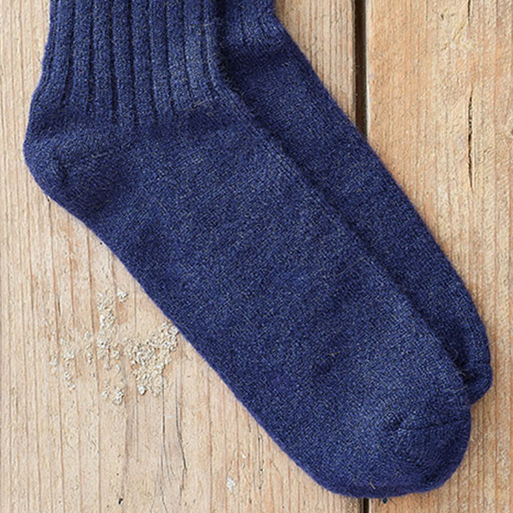 A pair of dark navy blue knit socks laid flat on a light wood plank surface.