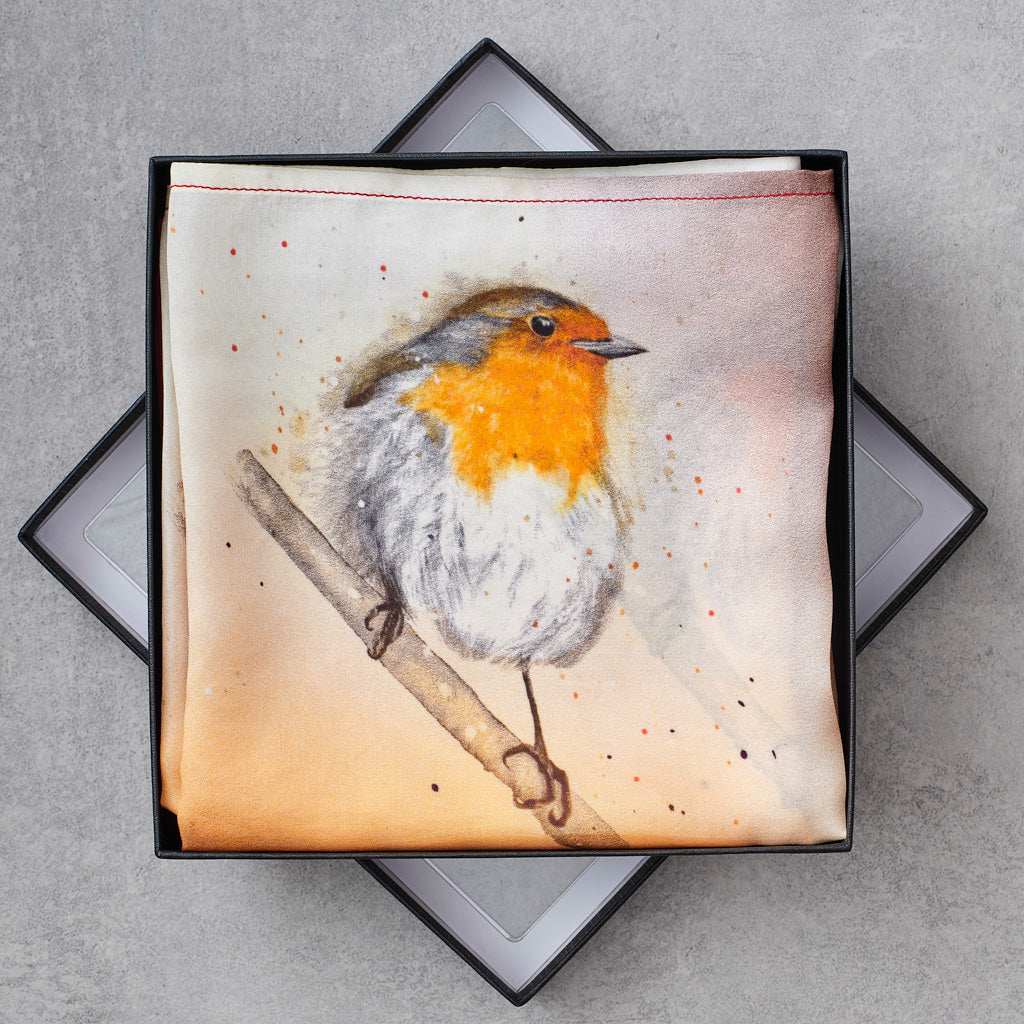A square fabric scarf with a watercolor-style robin bird perched on a branch, presented in an open black gift box on a gray surface.