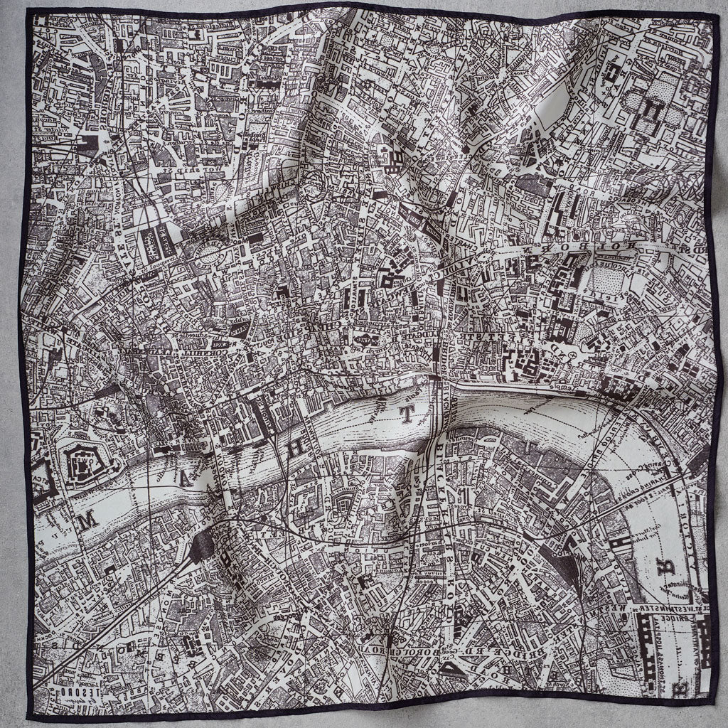 A square scarf featuring a detailed black and white vintage map print of London, bordered by a solid black edge, laid flat on a light gray fabric background.