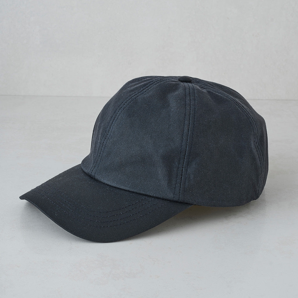 A dark charcoal gray baseball cap with a curved brim, photographed on a light gray textured studio background.