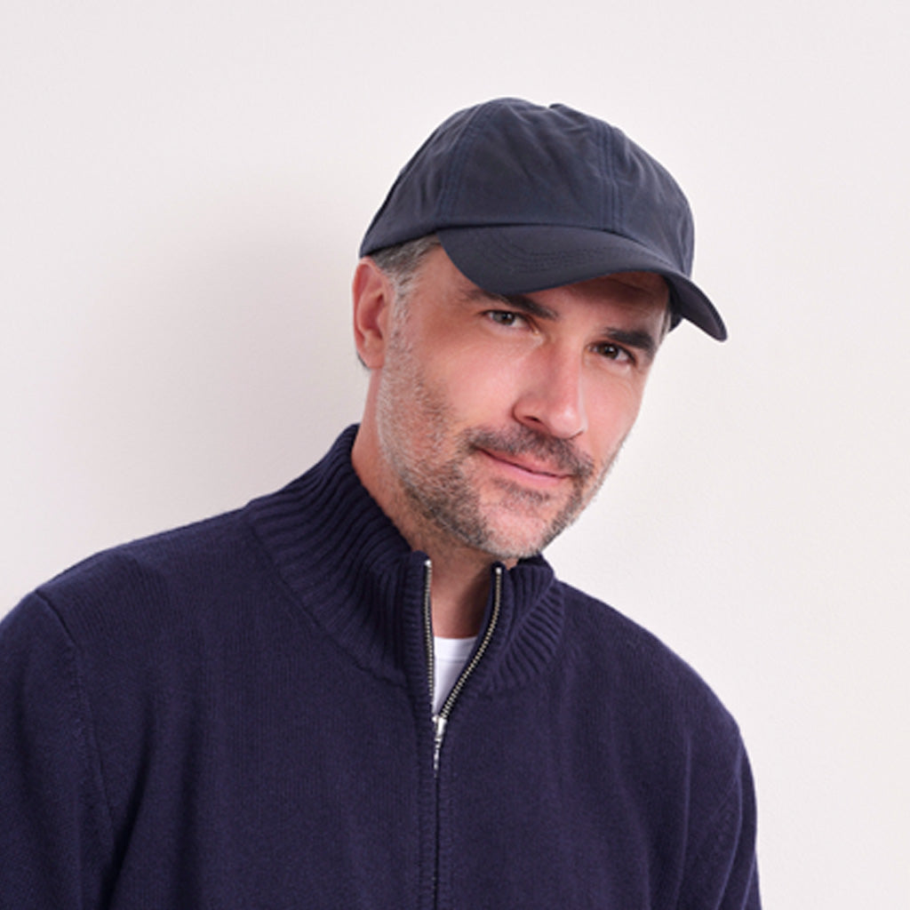A man wearing a dark navy blue knit quarter-zip sweater and a matching dark navy cap, photographed against a plain light background.