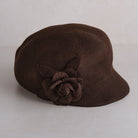 A dark brown felt cloche hat featuring a matching fabric flower and leaf embellishment on the side, set against a plain light background.