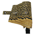 A folded leopard print umbrella on a black pole, featuring a tan and black pattern with the brand name 'tesoro' printed on the fabric.