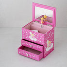 A pink children's jewelry box with a mirror on the lid, two drawers, and fairy illustrations with white stars. A small figurine stands on the inside of the lid.