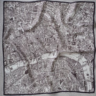 A square scarf featuring a detailed black and white vintage map print of London, bordered by a solid black edge, laid flat on a light gray fabric background.